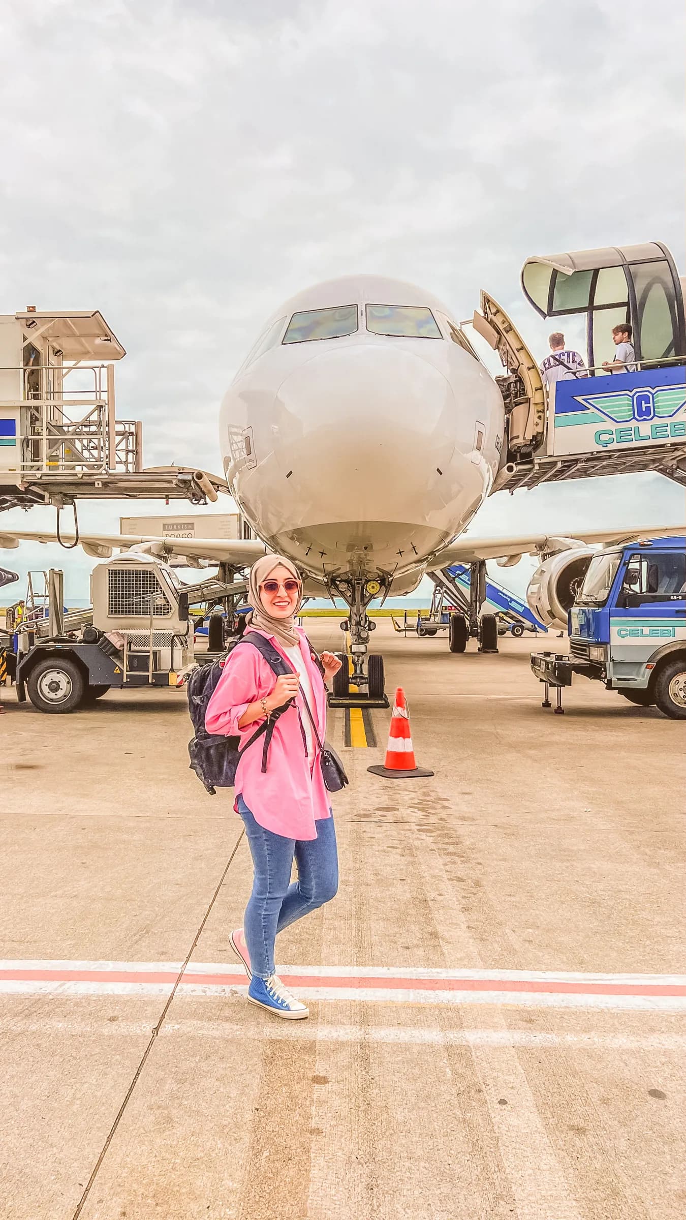 A traveller with a backpack on the apron in front of an aircraft, about to board